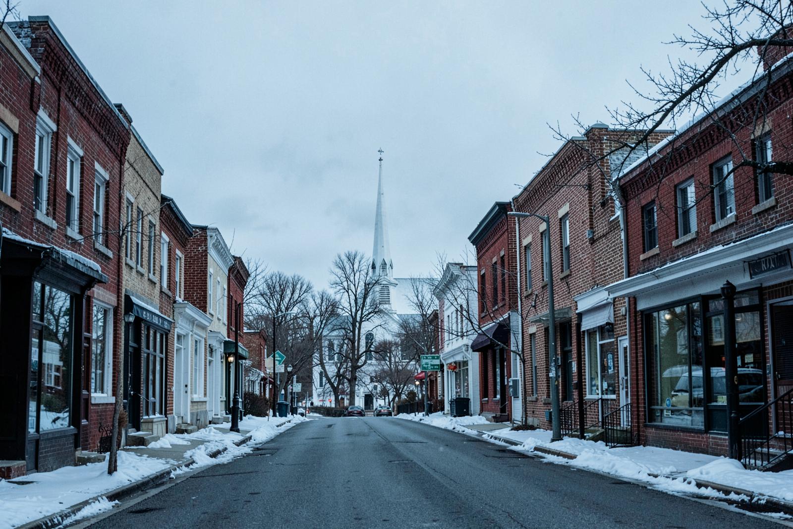 A New Hampshire main street of brick storefronts with a white church steeple beyond
